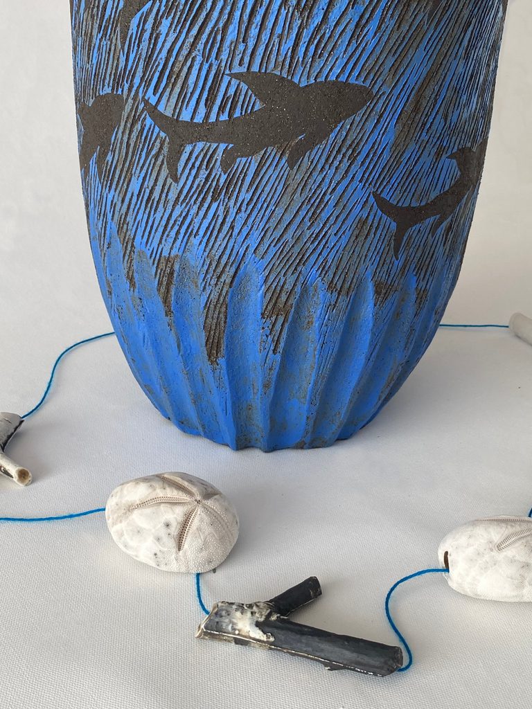 Bottom detail of a large sculptural stoneware vessel depicting sharks swimming against a deep blue background with marine elements, including sea urchins, by Alexandra Ridel