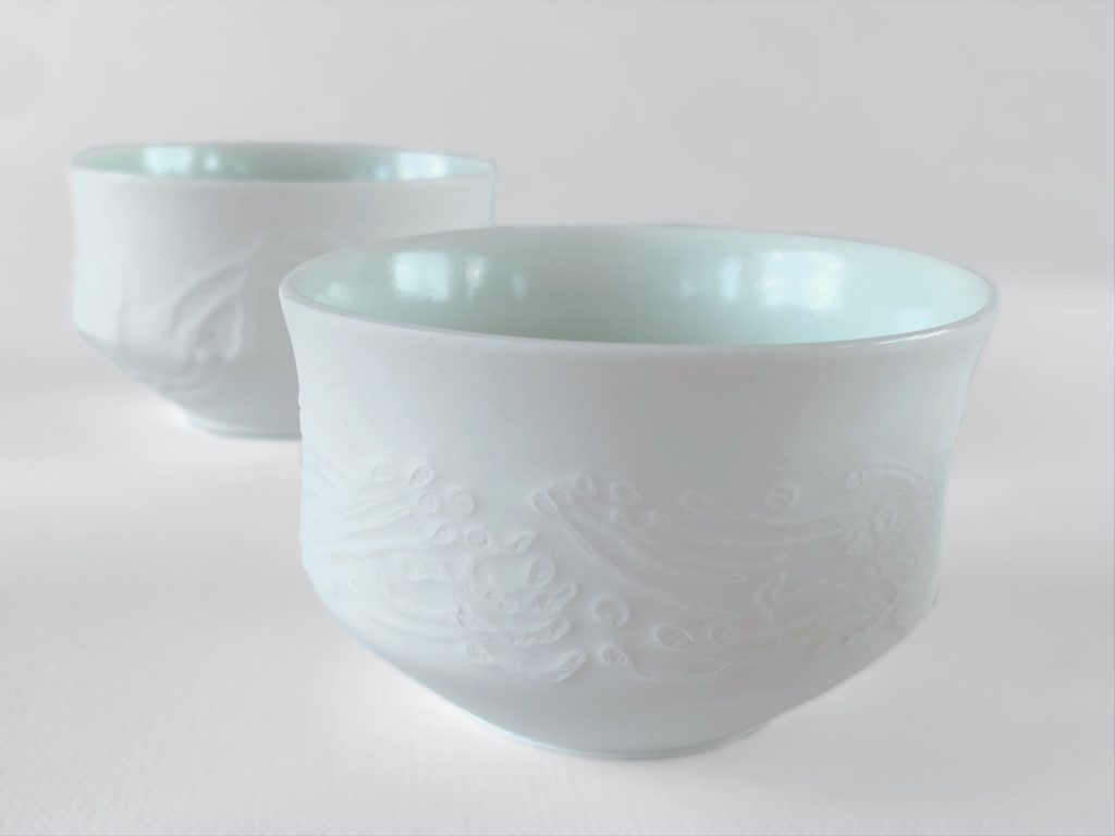 Collection of white porcelain cups with carved exterior decoration and light blue glaze, by Alexandra Ridel