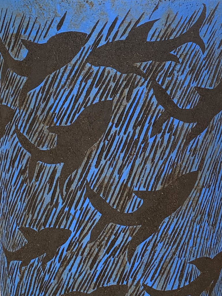 Close-up of a large sculptural stoneware vessel depicting sharks swimming against a deep blue background, by Alexandra Ridel