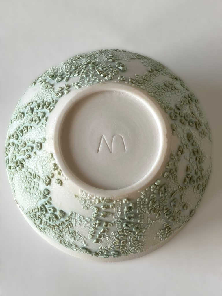 Foot and signature detail of a white porcelain bowl with green crawling glaze effect, by Alexandra Ridel