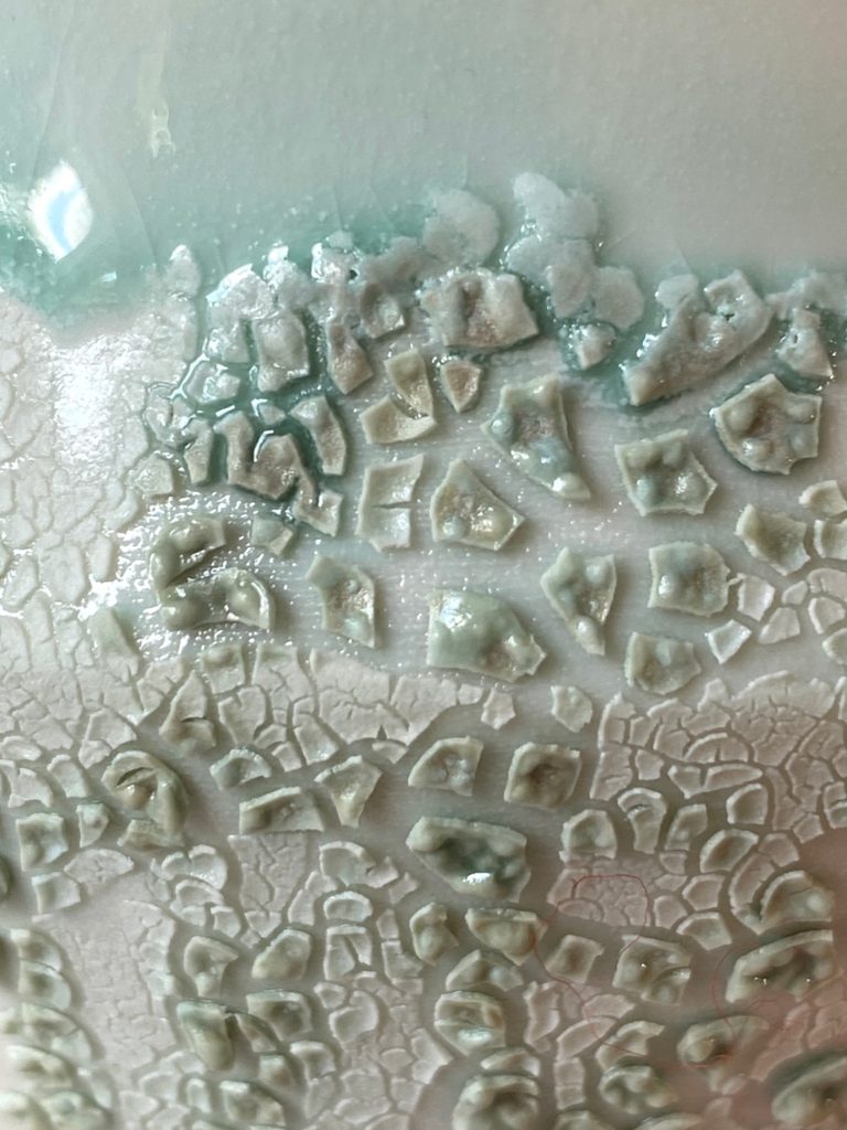 Close-up of white porcelain bowl with a green crawling glaze effect, by Alexandra Ridel