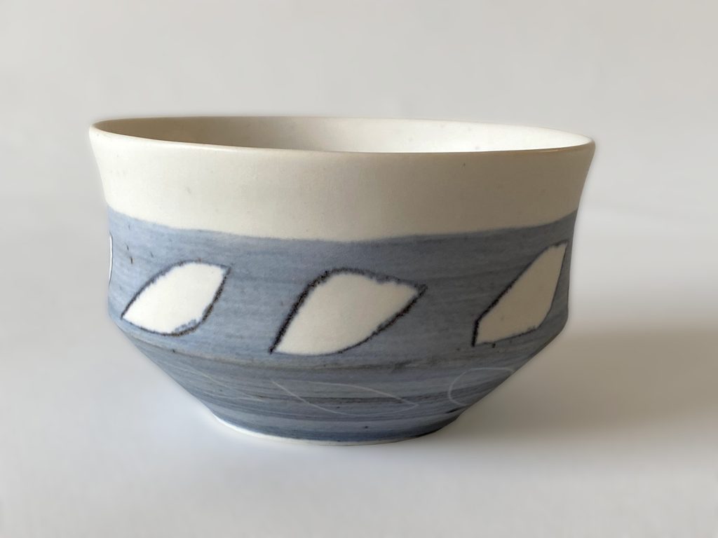 Handleless porcelain cup with repeating blue leaf motifs, by Alexandra Ridel